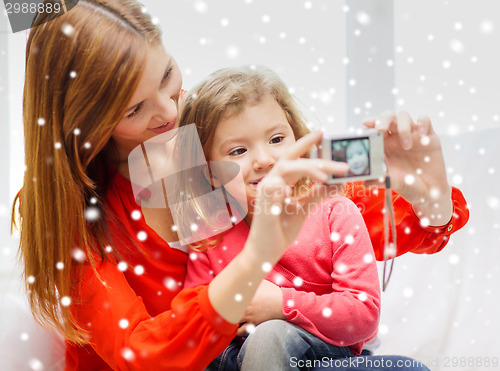 Image of smiling mother and daughter with camera