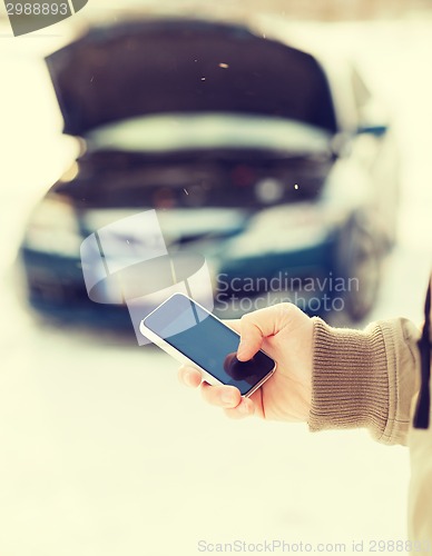 Image of closeup of man with broken car and cell tphone