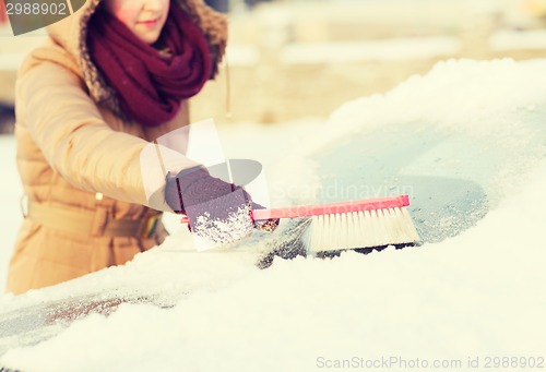 Image of woman cleaning snow from car back window