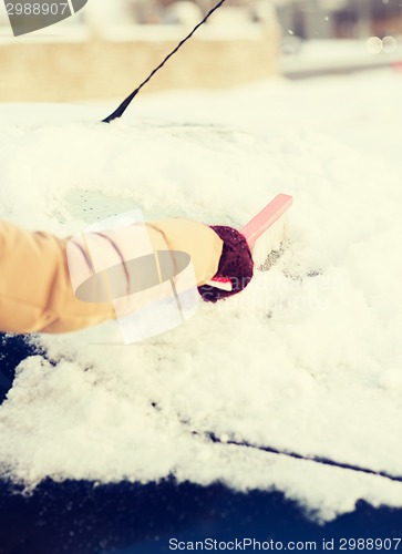 Image of woman cleaning snow from car back window