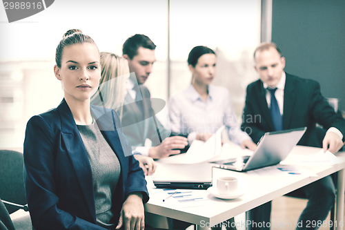 Image of businesswoman in office with team on the back