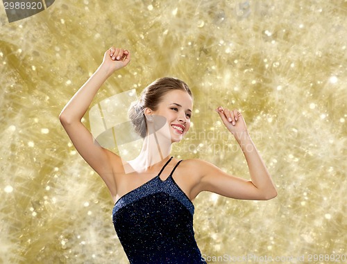 Image of smiling woman dancing with raised hands