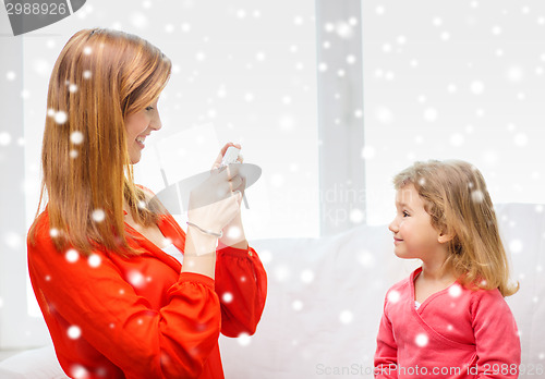 Image of smiling mother and daughter with camera