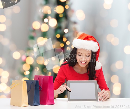 Image of smiling woman with shopping bags and tablet pc