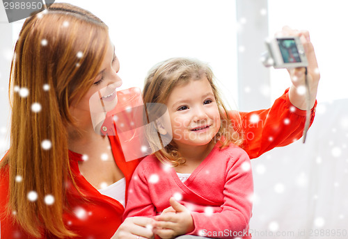 Image of smiling mother and daughter with camera