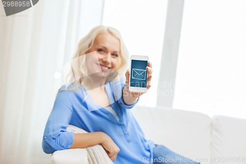 Image of smiling woman with smartphone at home