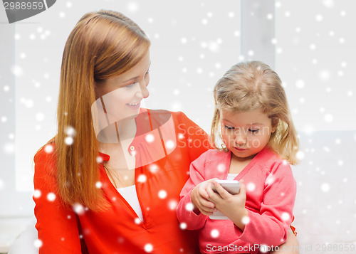 Image of happy mother and daughter with smartphone at home