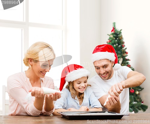 Image of happy family in santa helper hats cooking