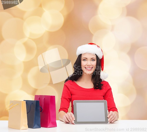 Image of smiling woman with shopping bags and tablet pc