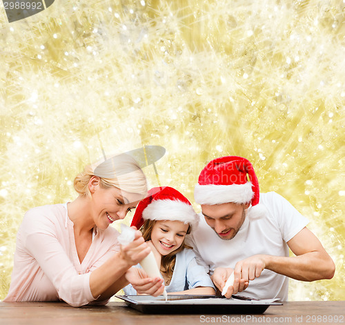 Image of happy family in santa helper hats cooking