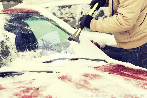 Image of closeup of man scraping ice from car