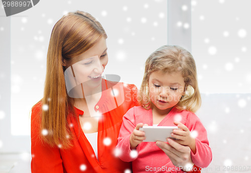 Image of happy mother and daughter with smartphone at home