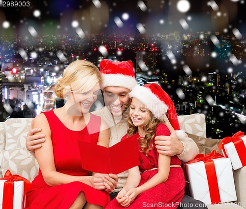 Image of happy family in santa helper hats with gift boxes