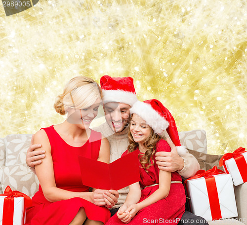 Image of happy family in santa helper hats with gift boxes