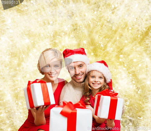 Image of happy family in santa helper hats with gift boxes
