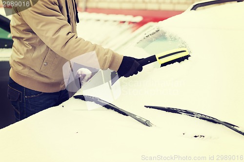 Image of closeup of man cleaning snow from car