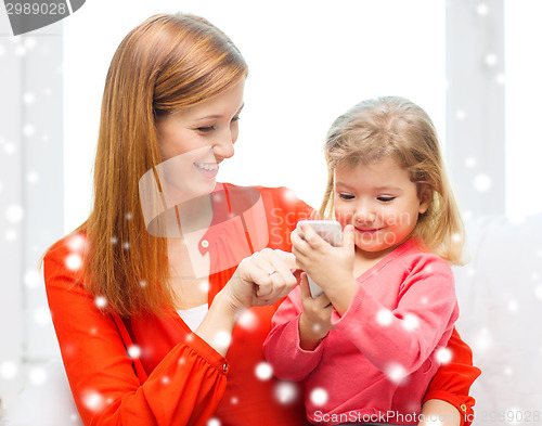 Image of happy mother and daughter with smartphone at home