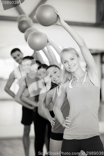 Image of group of smiling people working out with ball