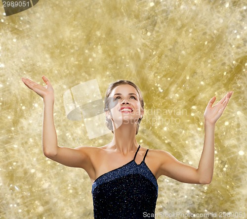 Image of smiling woman raising hands and looking up