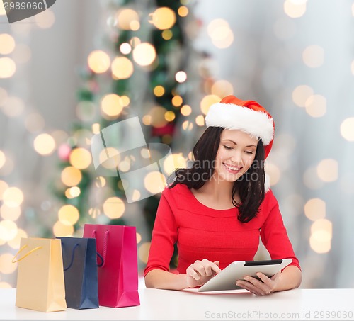 Image of smiling woman with shopping bags and tablet pc