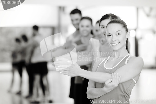 Image of group of smiling people stretching in the gym