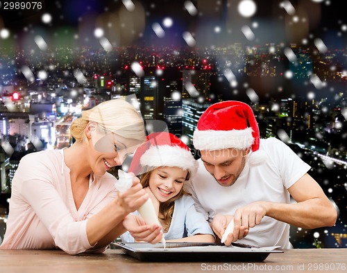 Image of happy family in santa helper hats cooking