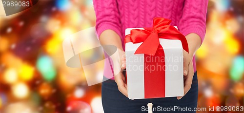 Image of close up of woman in pink sweater holding gift box