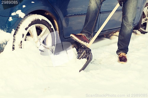 Image of closeup of man digging up stuck in snow car