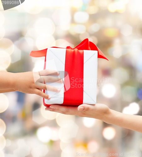 Image of close up of child and mother hands with gift box