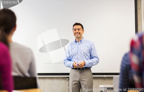 Image of group of students and smiling teacher in classroom