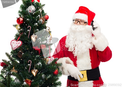 Image of santa claus with smartphone and christmas tree