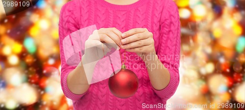 Image of close up of woman in sweater with christmas ball