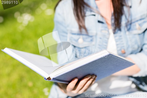 Image of close up of young girl with book in park