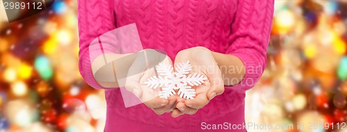 Image of close up of woman in sweater holding snowflake