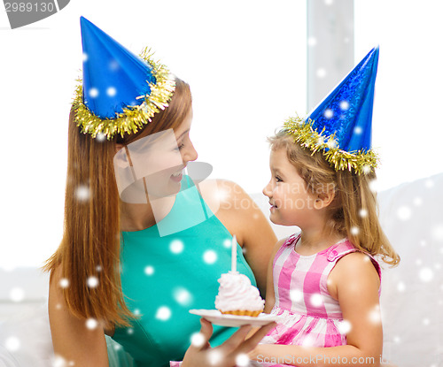 Image of mother and daughter in party hats with cake