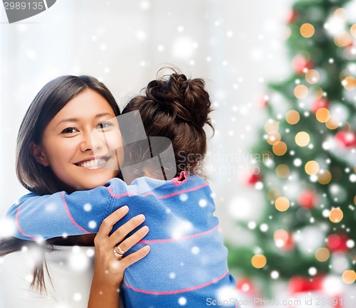 Image of smiling little girl and mother hugging indoors