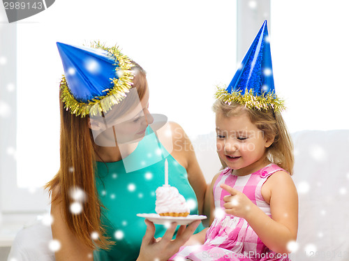 Image of mother and daughter in party hats with cake