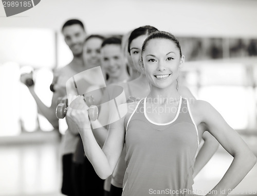 Image of group of smiling people with dumbbells in the gym