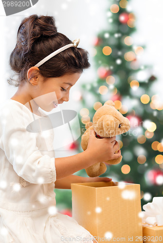 Image of smiling little girl with gift box and teddy bear