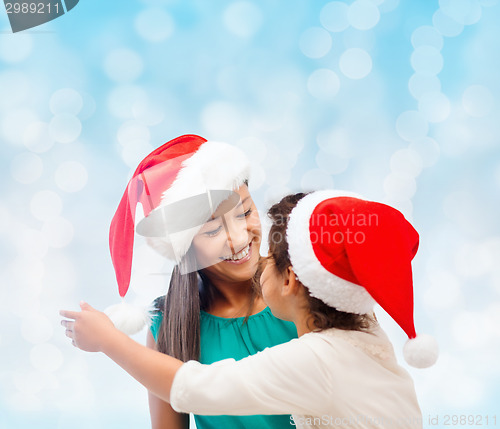 Image of happy mother and girl in santa hats