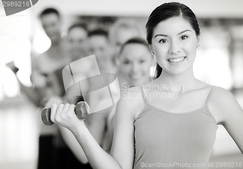 Image of group of smiling people with dumbbells in the gym