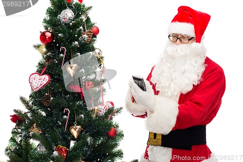 Image of santa claus with smartphone and christmas tree