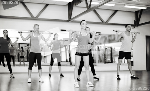 Image of group of smiling people working out with barbells