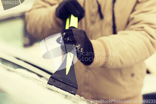 Image of closeup of man scraping ice from car