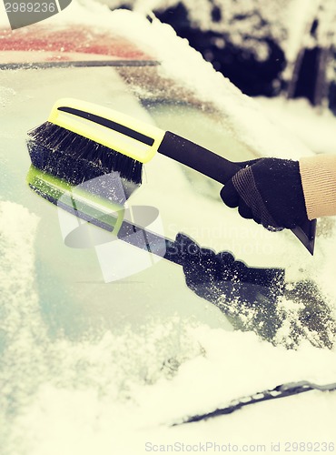 Image of closeup of man cleaning snow from car