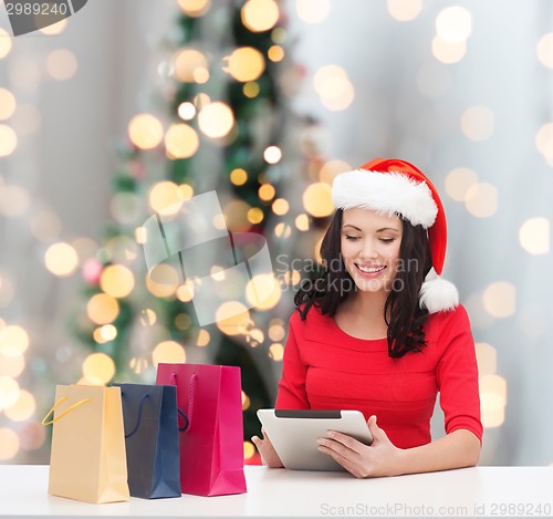 Image of smiling woman with shopping bags and tablet pc