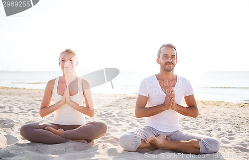 Image of smiling couple making yoga exercises outdoors
