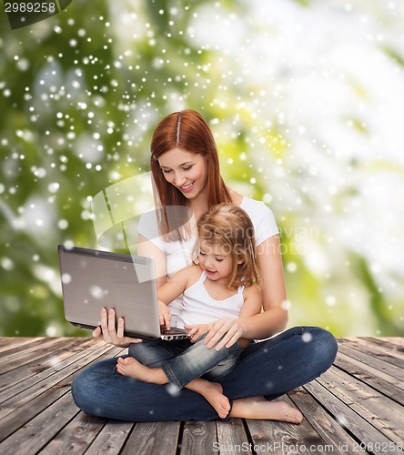 Image of happy mother with little girl and laptop