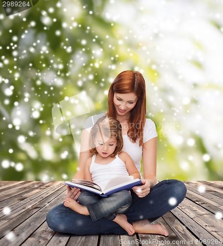 Image of happy mother with little girl and book