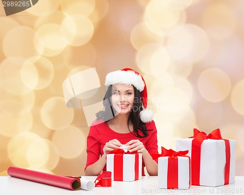 Image of smiling woman in santa helper hats packing gifts